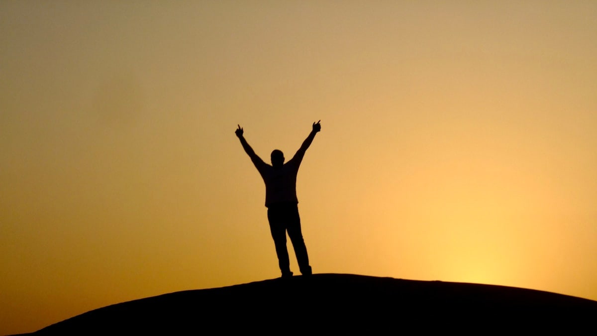 a person standing on top of a hill with their arms in the air